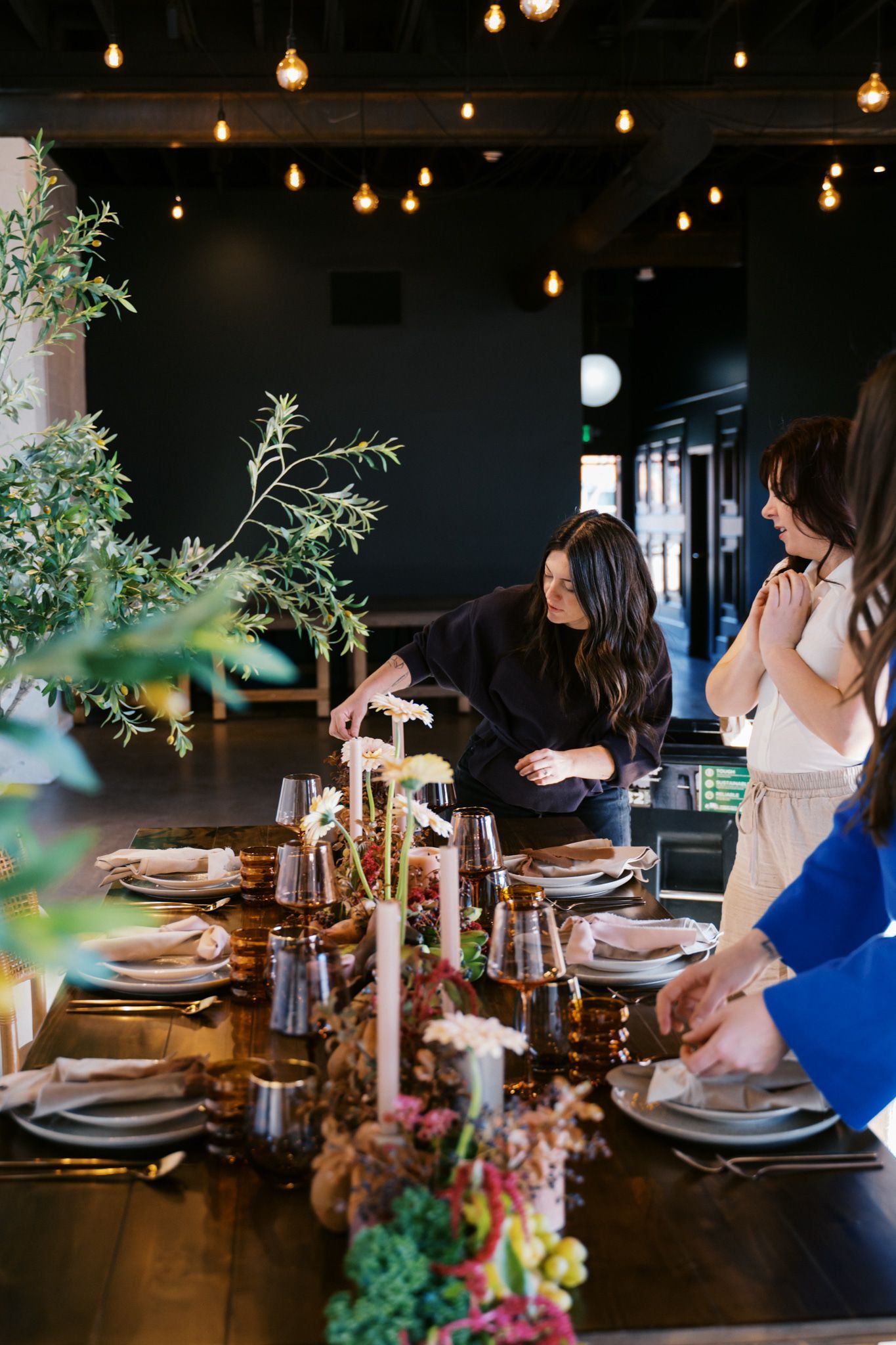 Florist lighting candles on a decorated tabletop at Bestow Events.