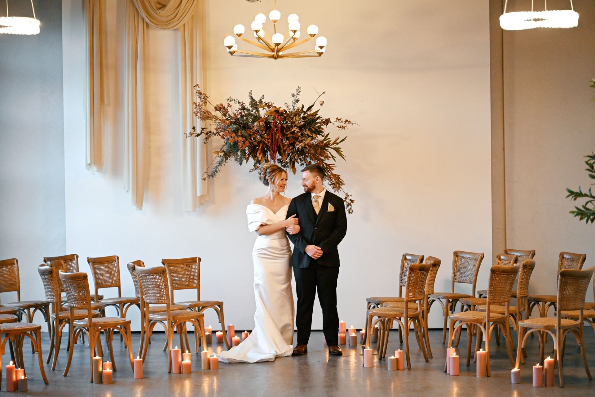 Bride and groom posing beneath florals and chandelier at Bestow Events in Longmont, CO.
