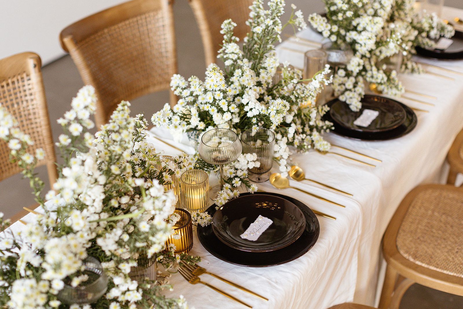 White and green florals on top of farm tables at Bestow Events in Longmont, CO.