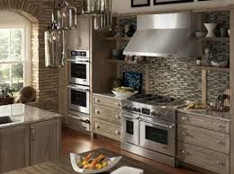 Upscale kitchen with stainless steel appliances, light wood cabinets, and a mosaic tile backsplash.