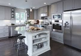 Modern gray kitchen with stainless steel appliances, a white island with shelving, and dark wood floors.
