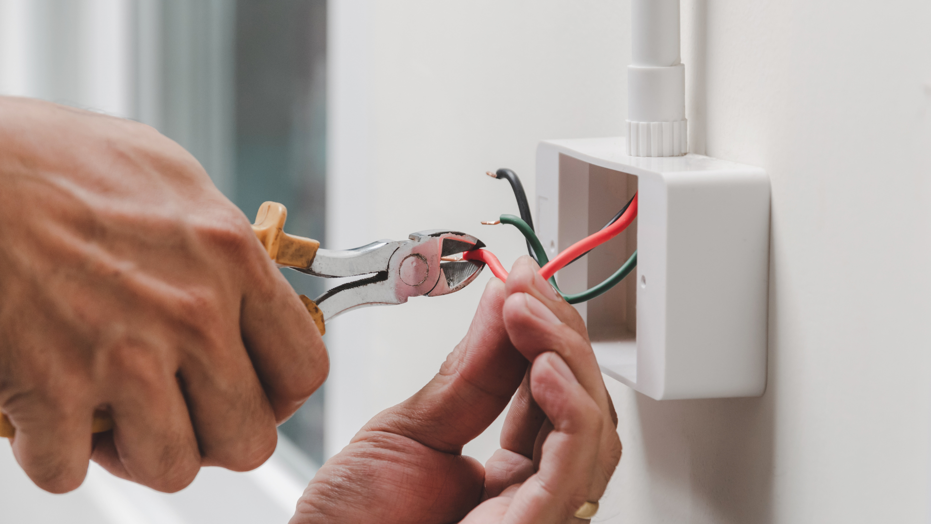 A person is working on an electrical box on a wall.