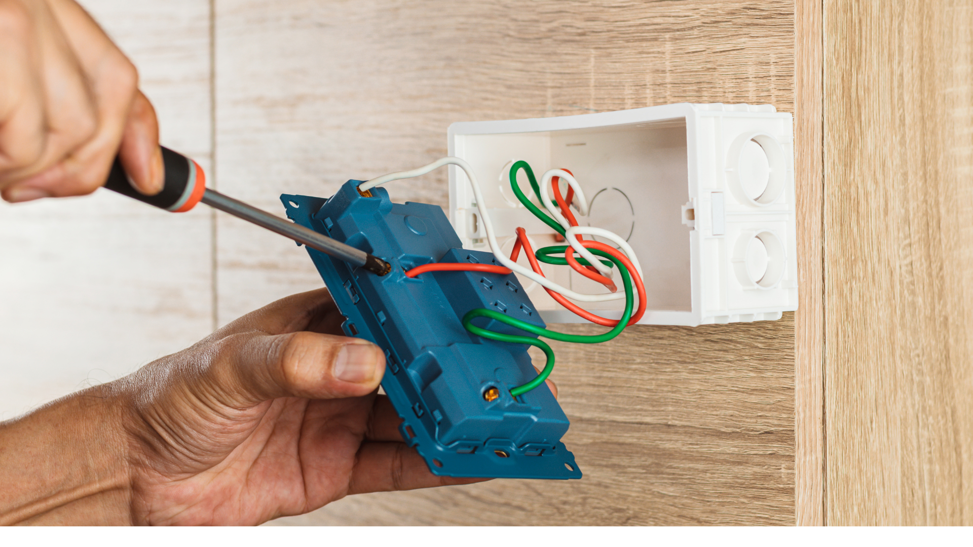 A person is fixing a light switch with a screwdriver.