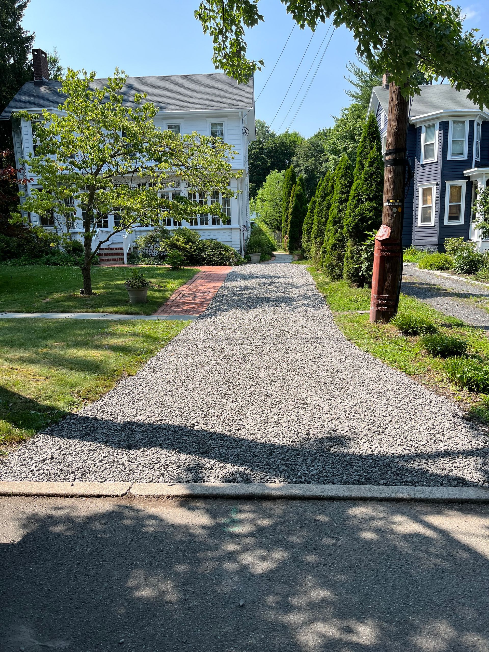 A gravel driveway leading to a house on a sunny day