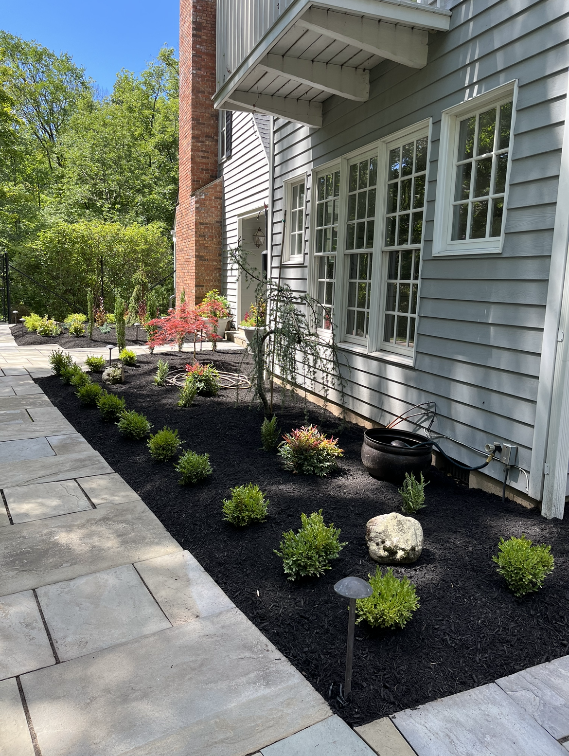 A house with a patio and a garden in front of it.