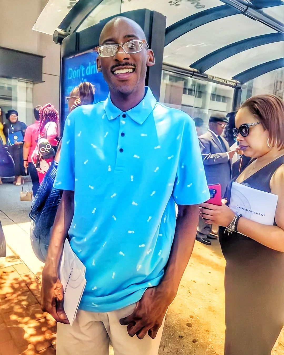 A man wearing glasses and a blue shirt is smiling