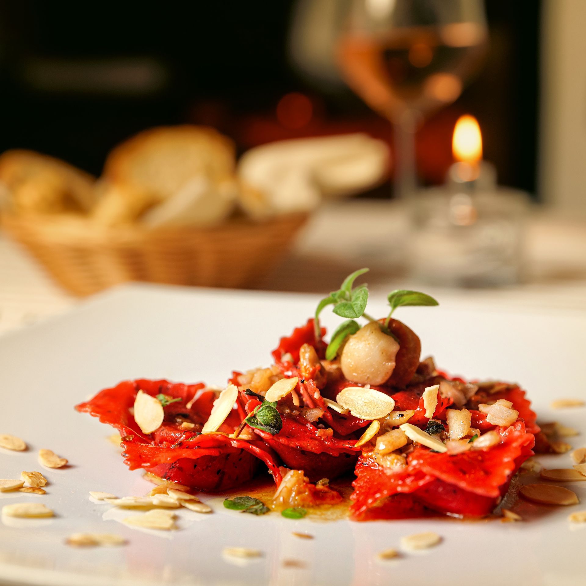 Ravioli gourmet guarniti con erbe aromatiche e frutta secca, serviti su un piatto in un ristorante dall'atmosfera soffusa.