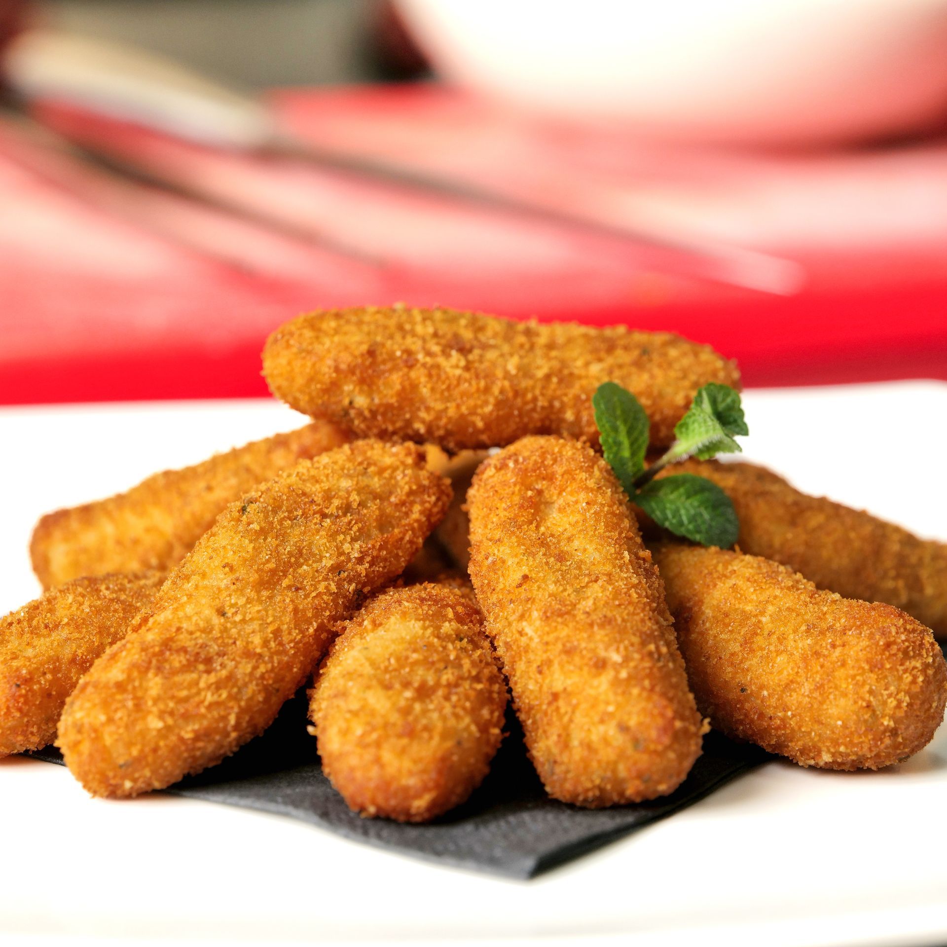 Crocchette fritte impanate, impilate su un piatto e guarnite con prezzemolo.