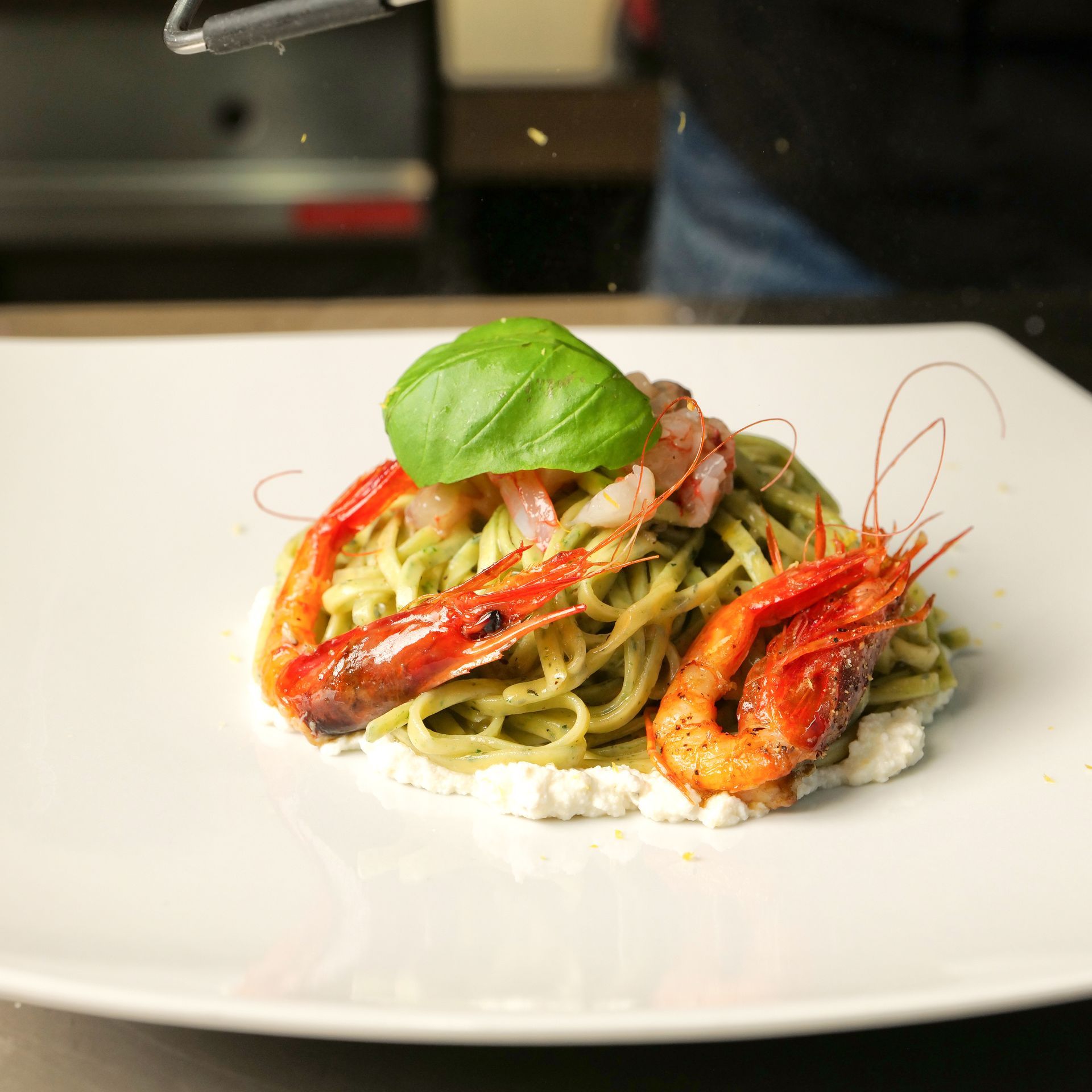 Pasta con gamberi e basilico servita su un piatto bianco.