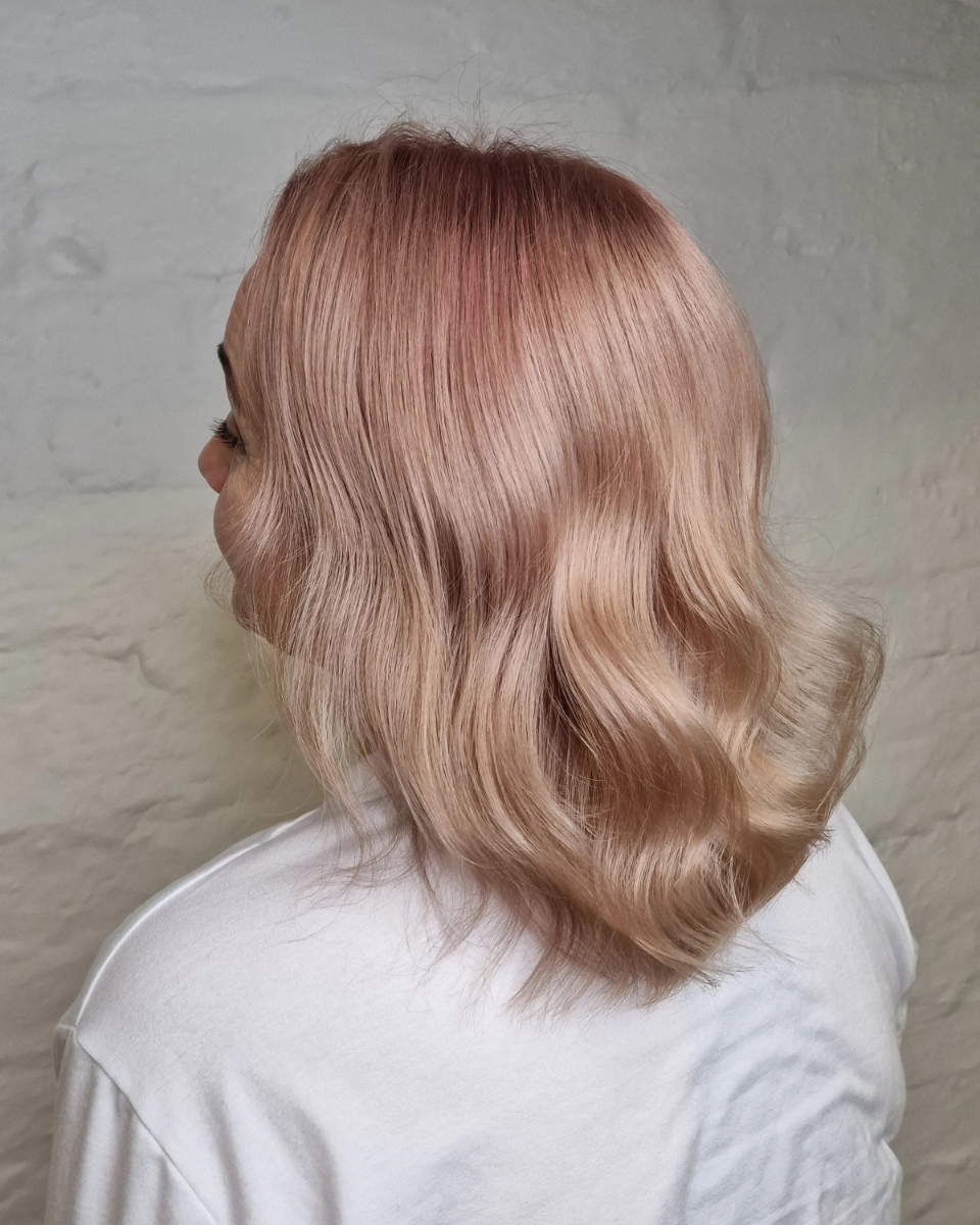 A woman with pink hair is wearing a white shirt.
