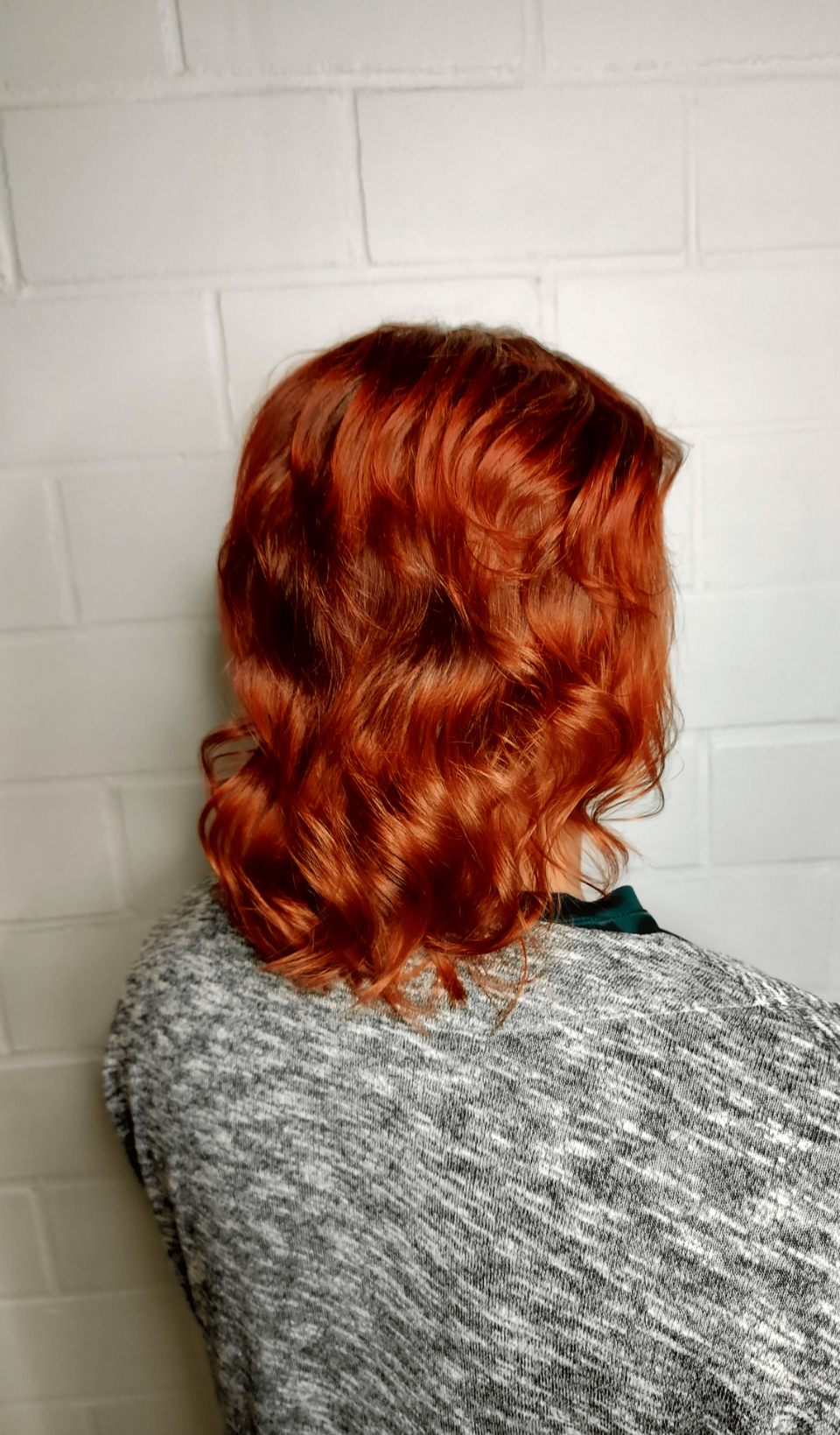 A woman with red hair is wearing a gray sweater.