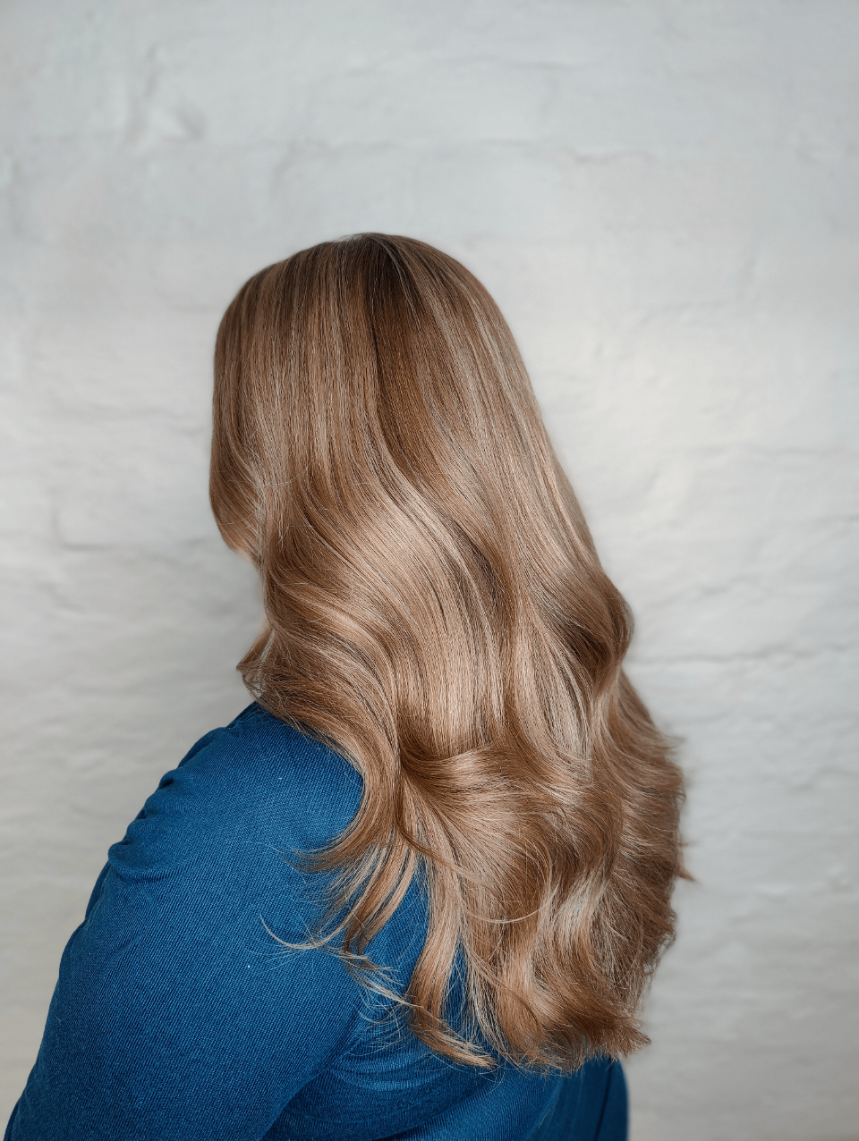 A woman with long blonde hair is wearing a blue sweater.