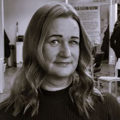 A woman with long hair is standing in front of a mirror in a black and white photo.