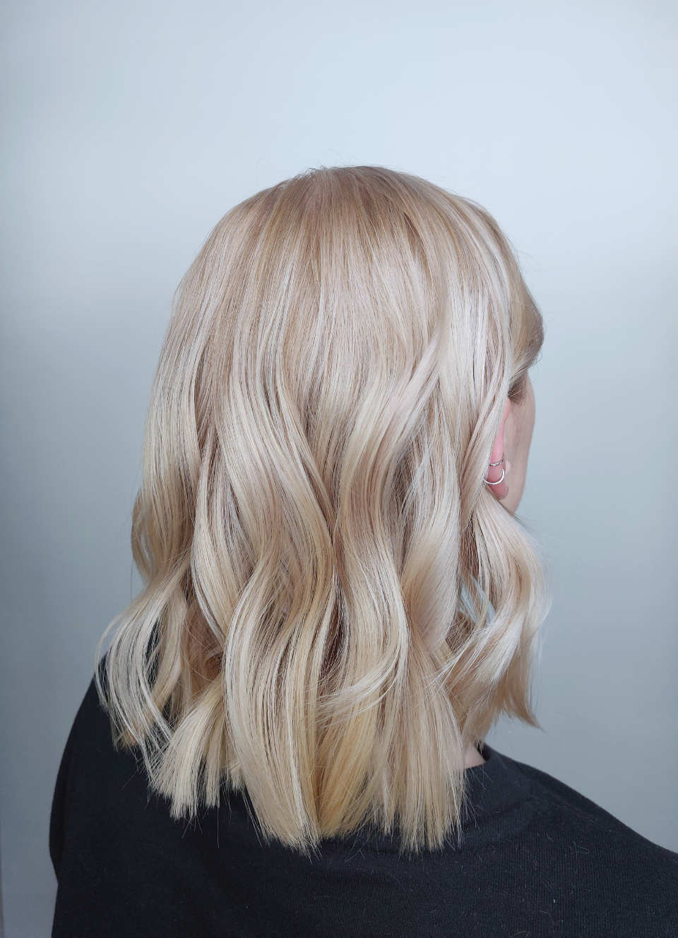 A woman with blonde hair is wearing a black shirt.