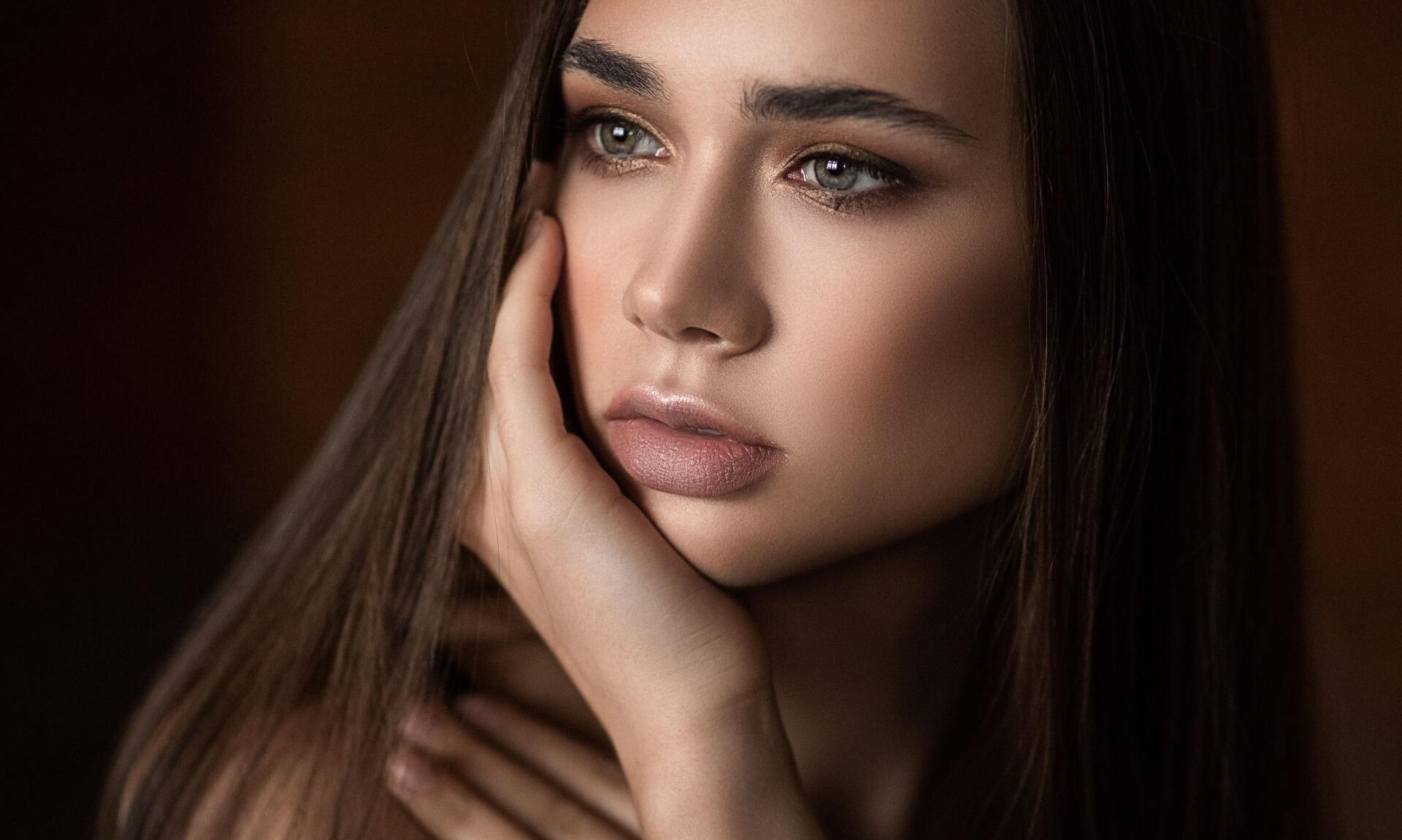 A close up of a woman 's face with her hand on her face.