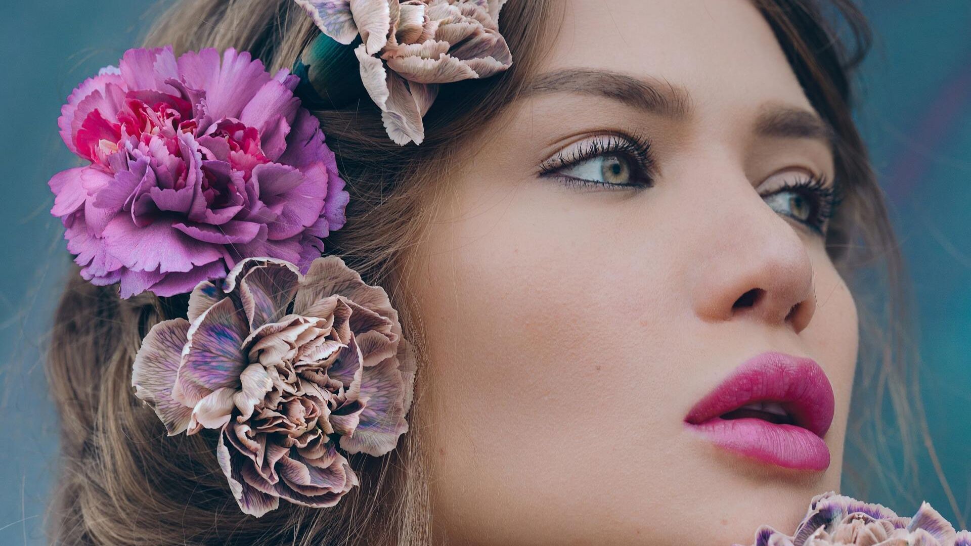 A close up of a woman 's face with flowers in her hair.