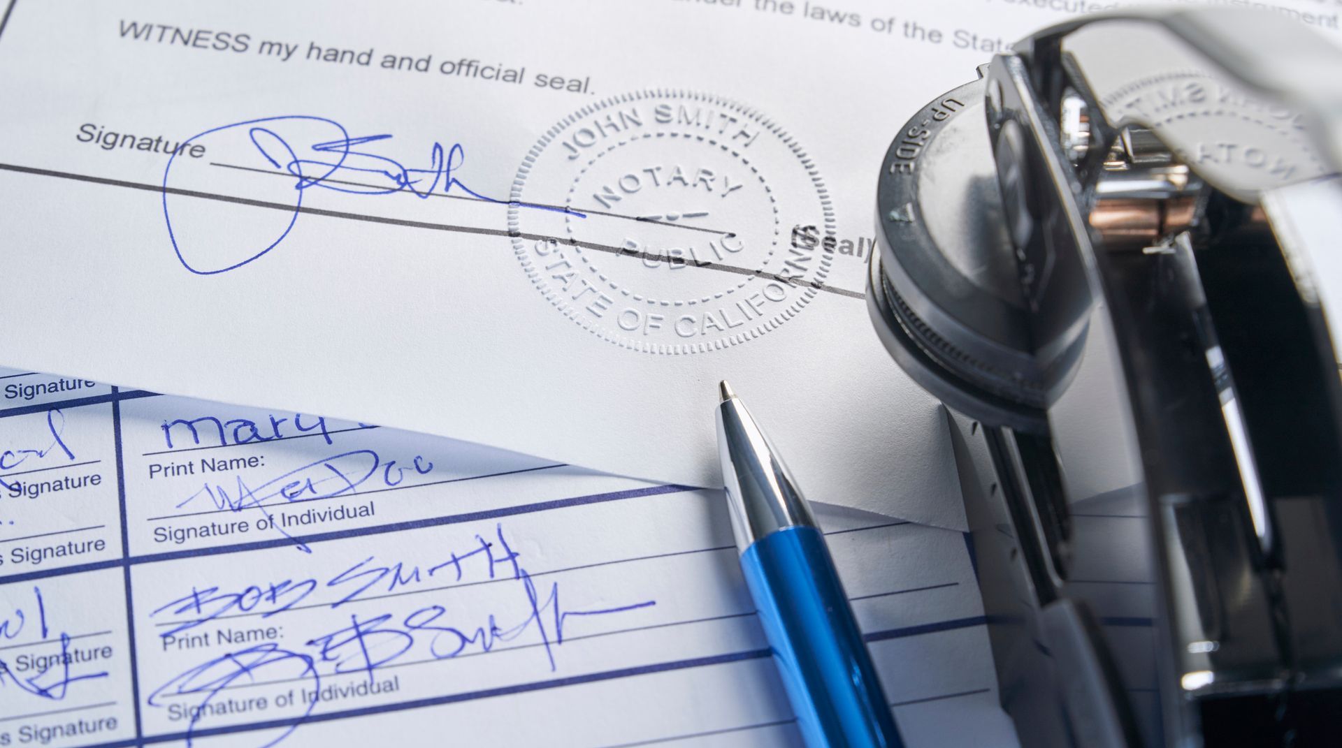 Documentos legales firmados con sello notarial, bolígrafo y grapadora.