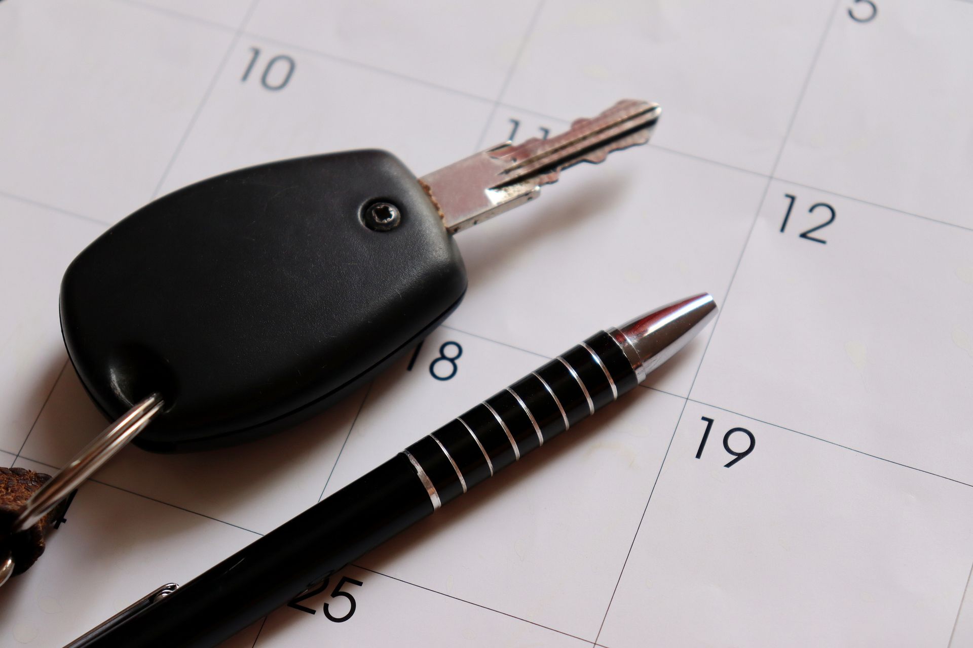 Llaves del coche y bolígrafo sobre un calendario, posiblemente para programar una cita con el vehículo.