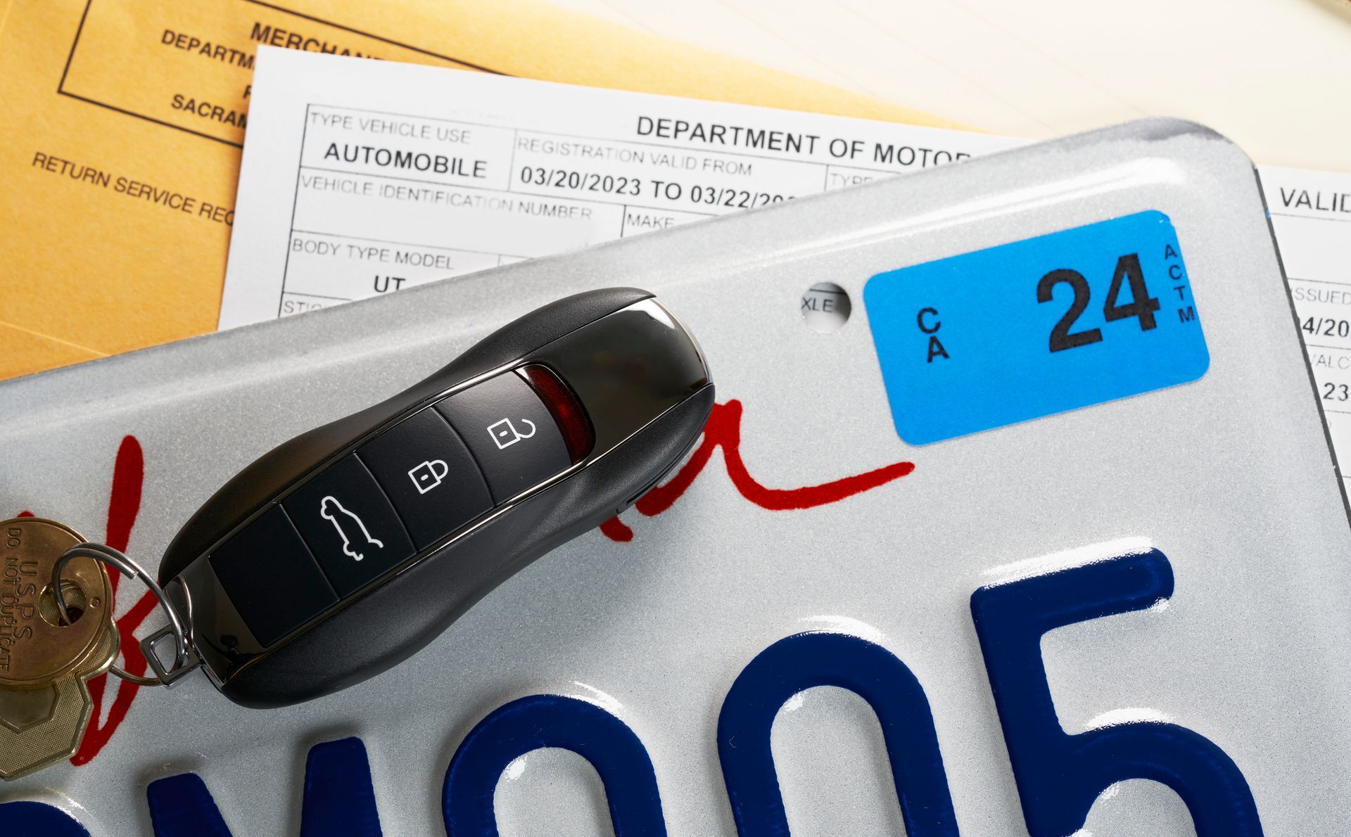 Car key on California license plate with registration sticker and paperwork. Car key on California license plate with registration sticker and paperwork.