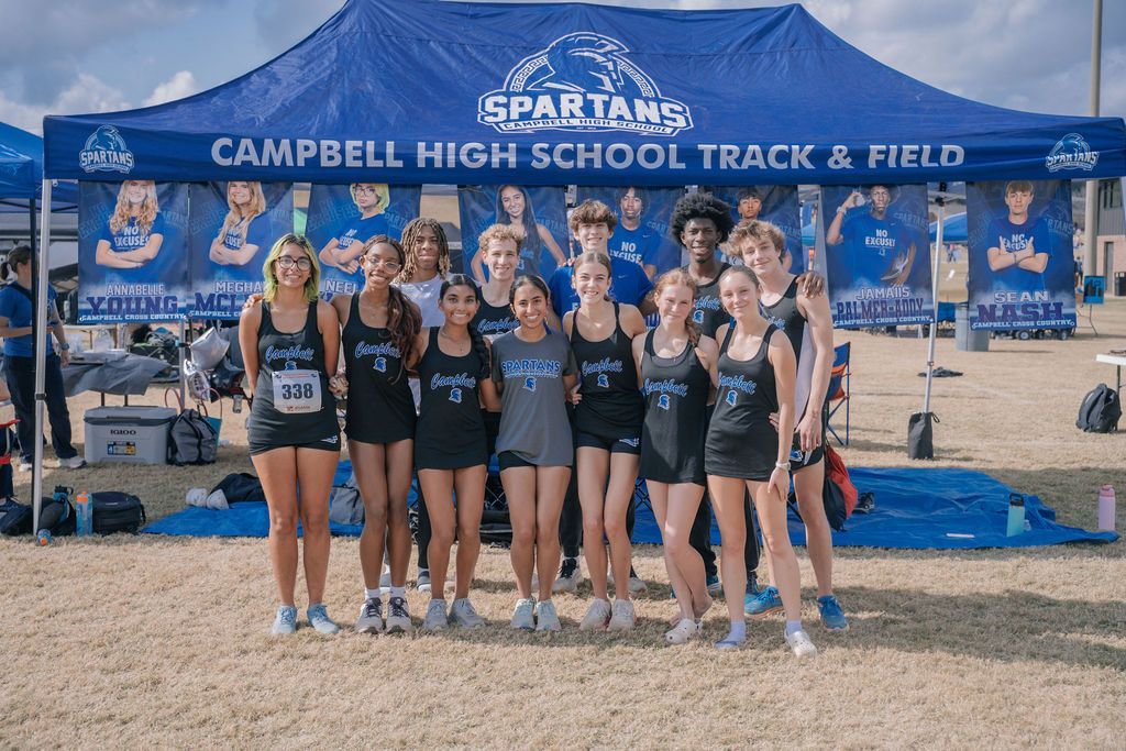 Campbell High School track team posing under blue Spartans tent at a meet
