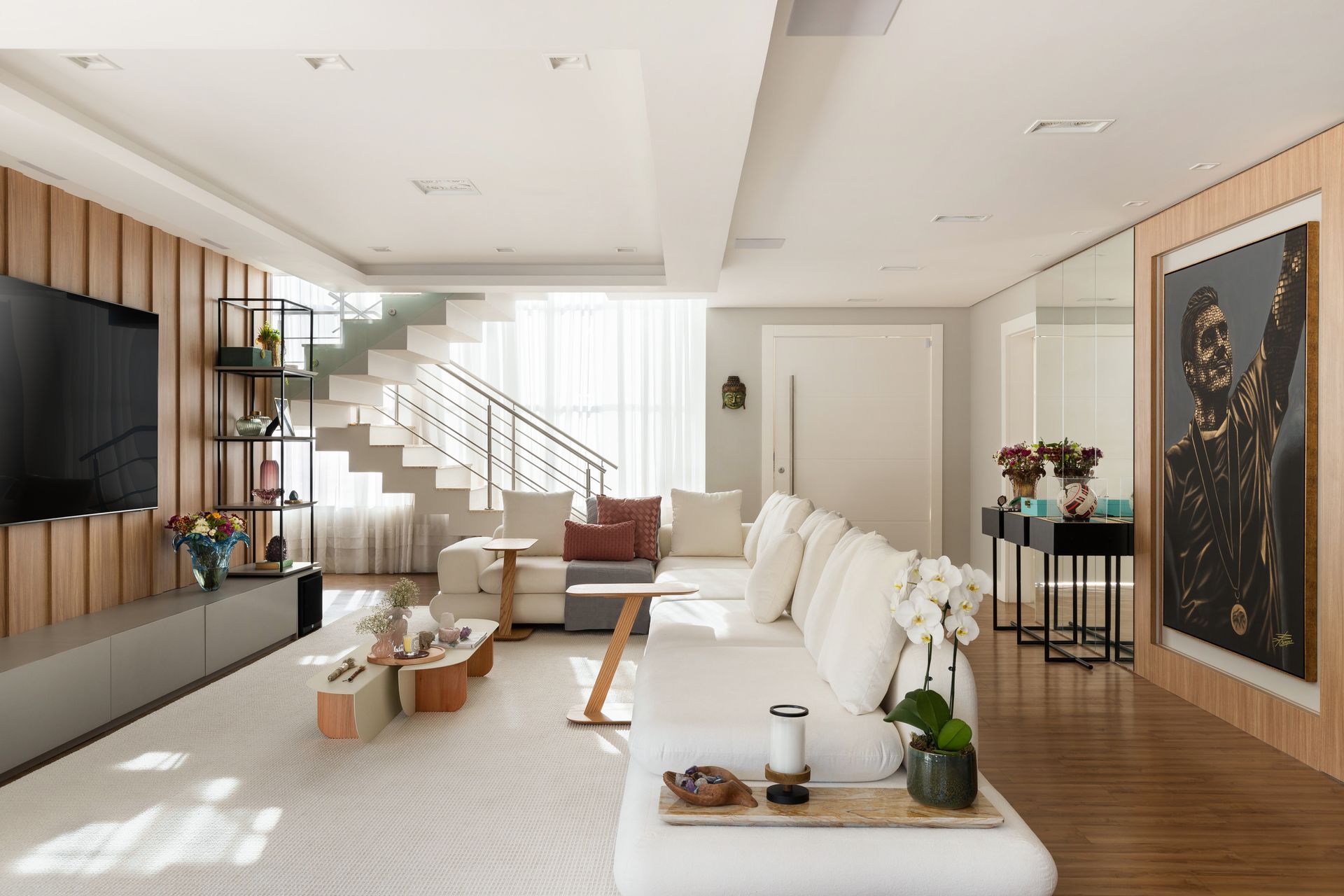 Uma sala de estar com um sofá, televisão e escadas.