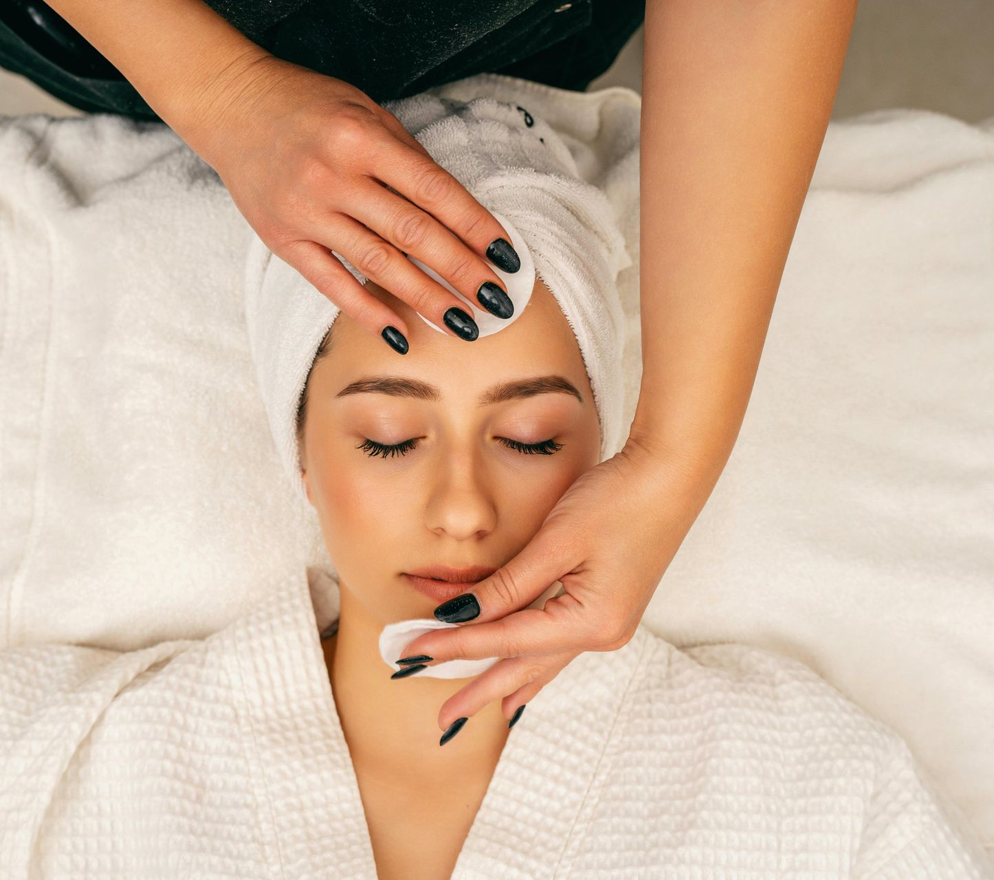 Donna che riceve un trattamento viso con dischetti di cotone, in un centro benessere.