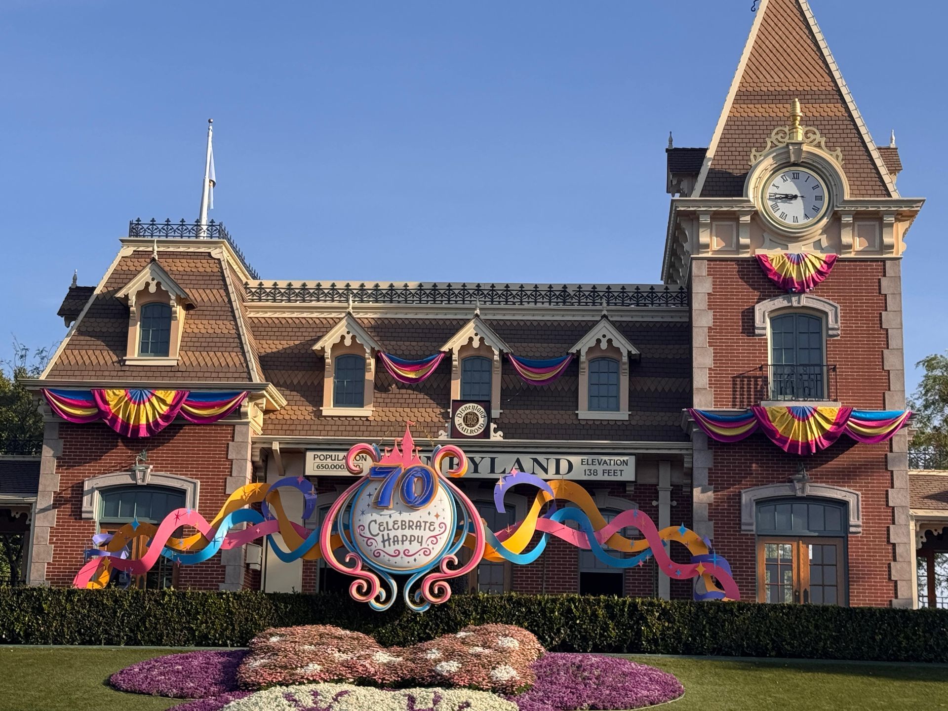 Decorated Victorian-style building with colorful 100th anniversary bunting and floral landscaping