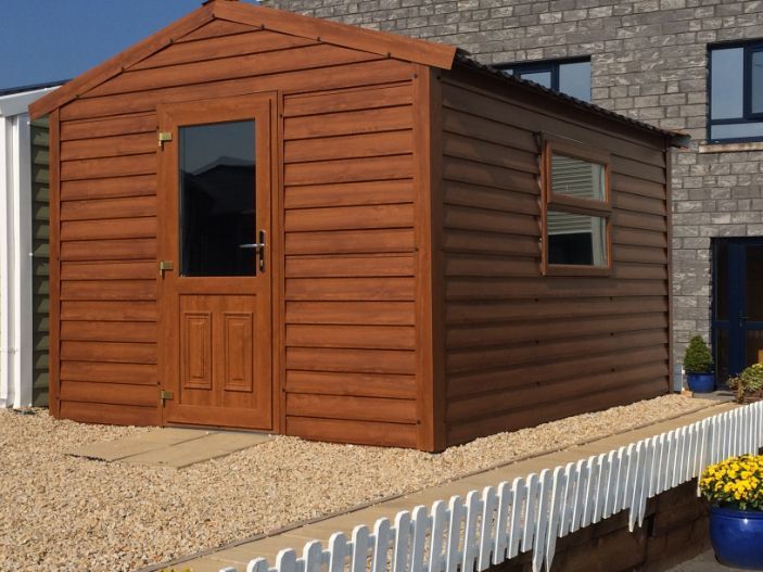 A wooden shed with a glass door is in front of a brick building