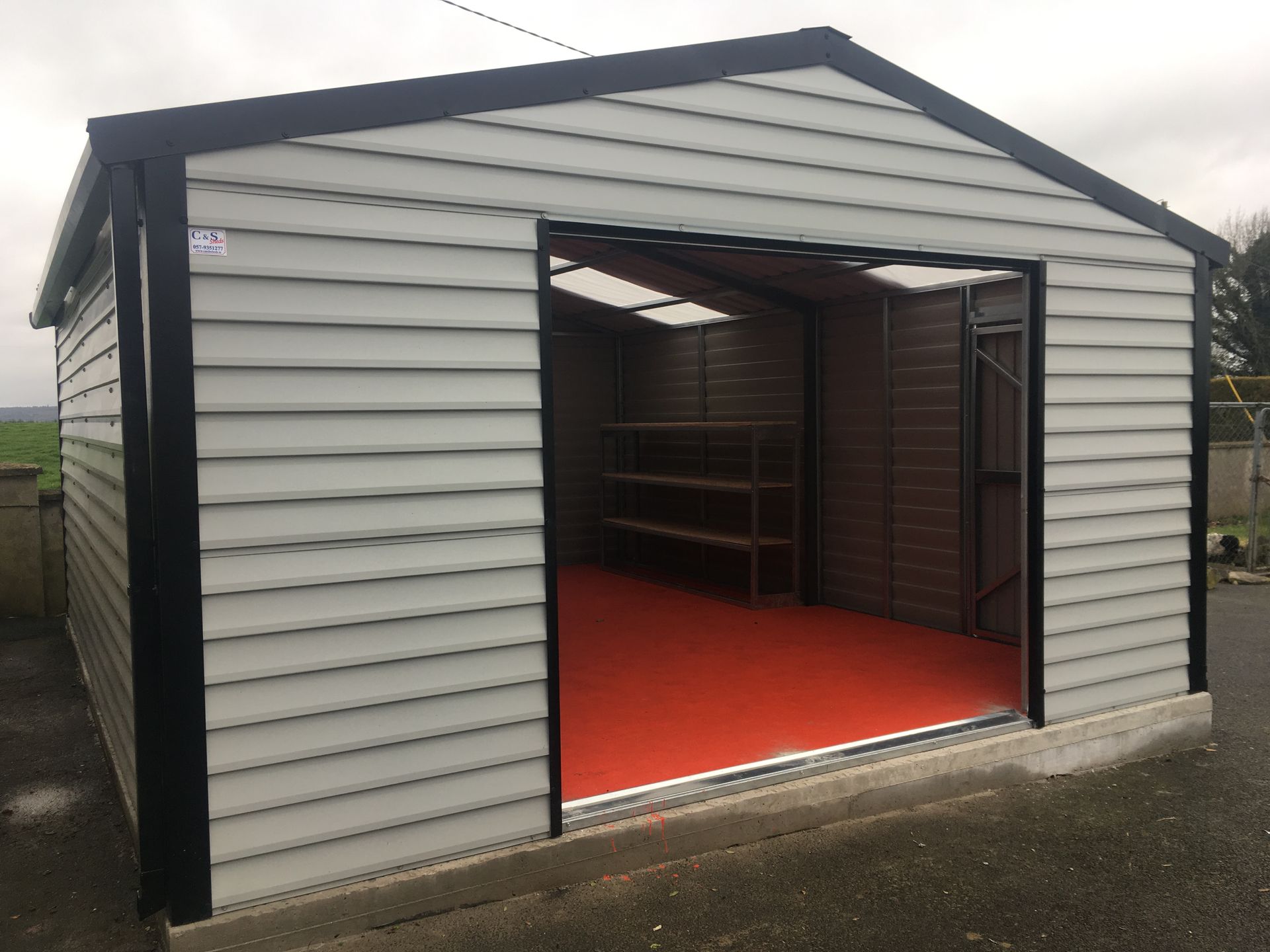 A garage with the door open and a red floor