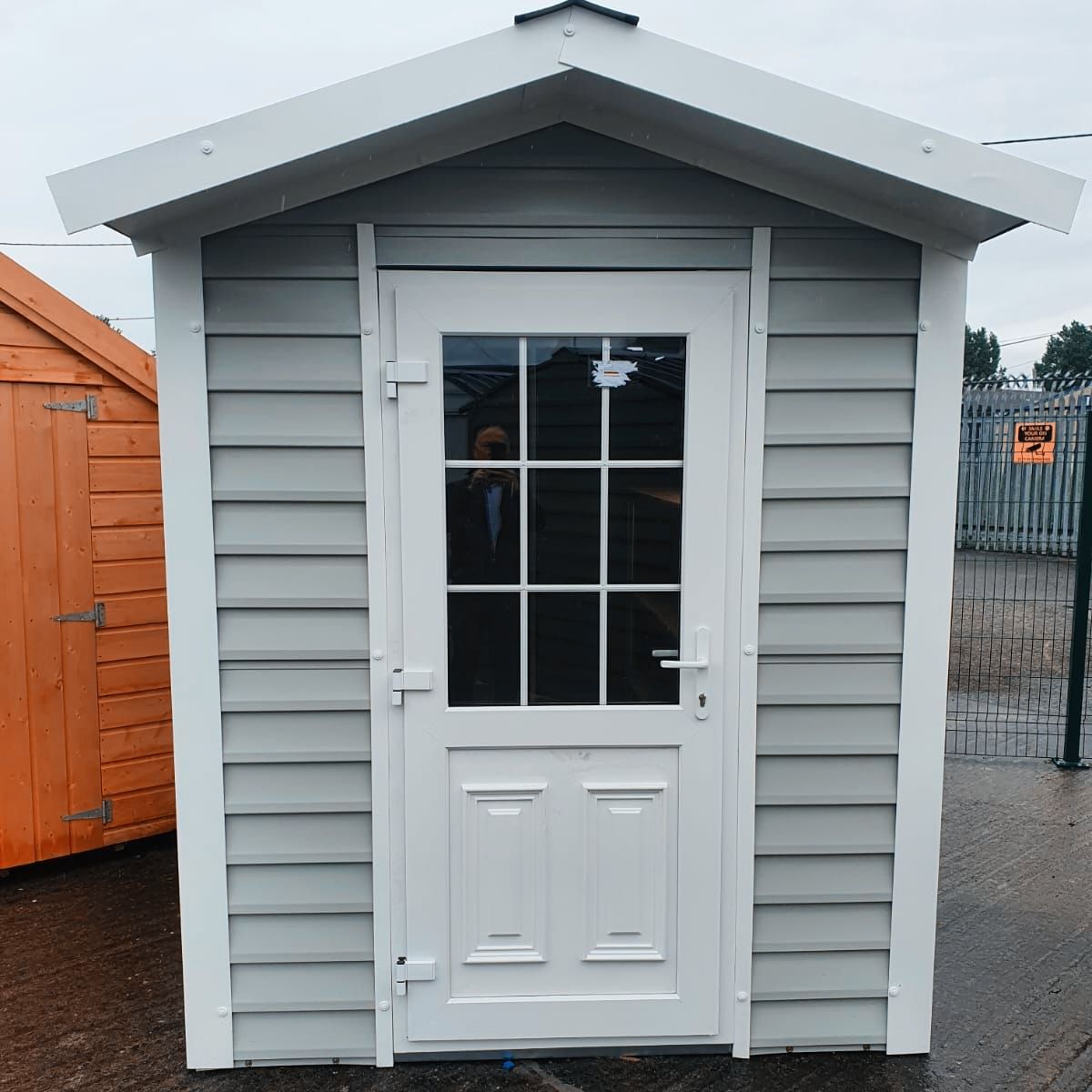 A small white shed with a glass door