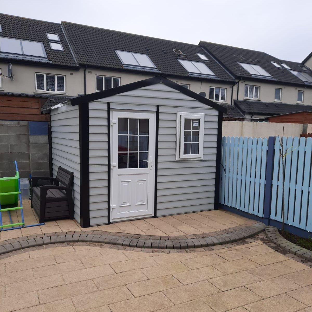 A small shed in a backyard with a blue fence