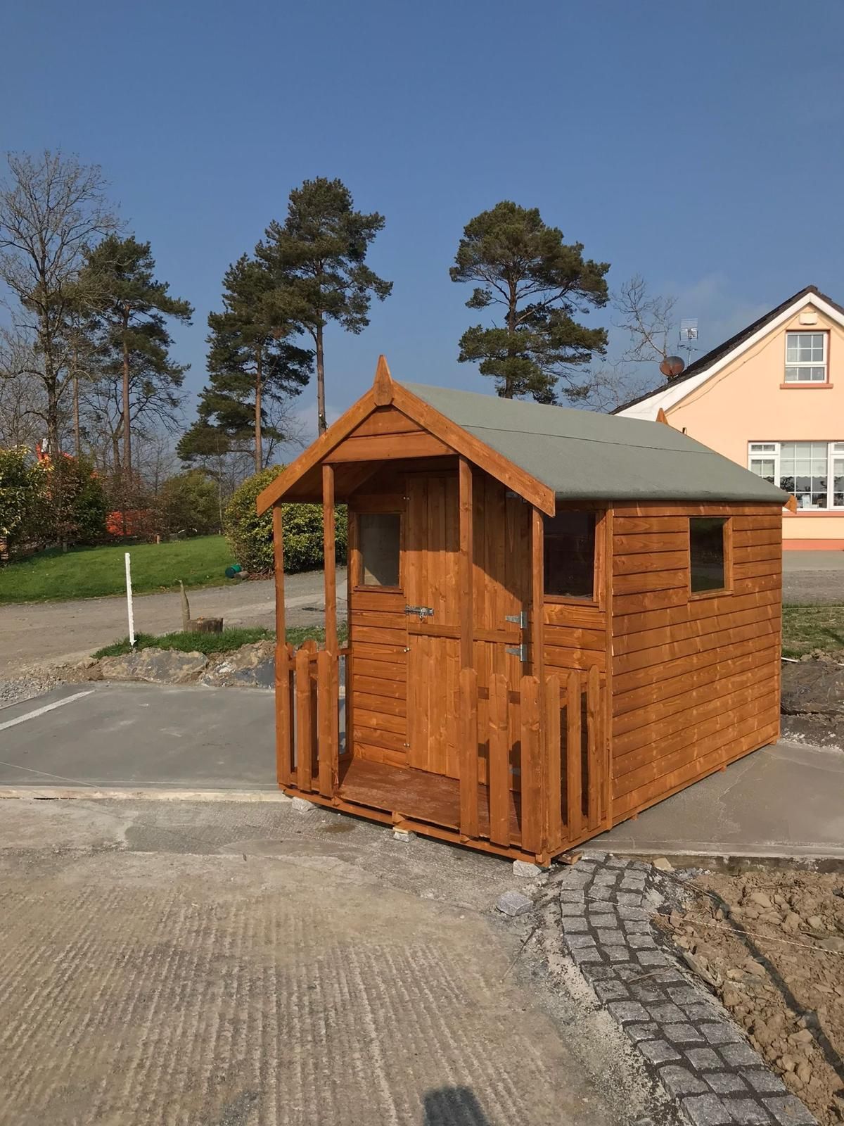 A small wooden shed with a porch in front of a house