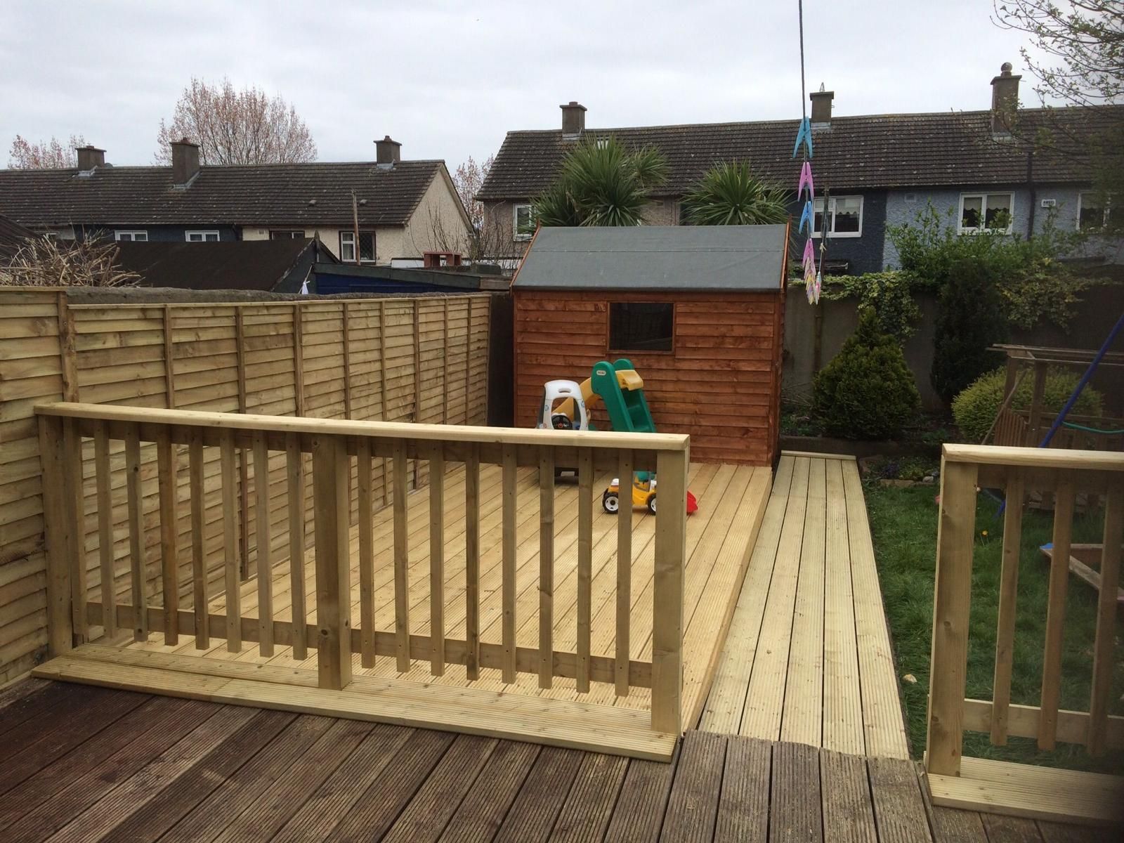 A wooden deck with a fence and a shed in the backyard