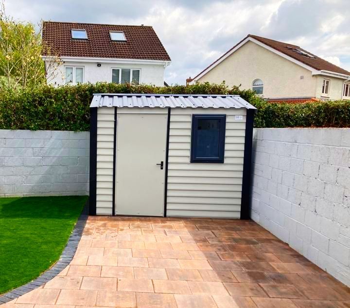 A white shed is sitting in the backyard of a house.