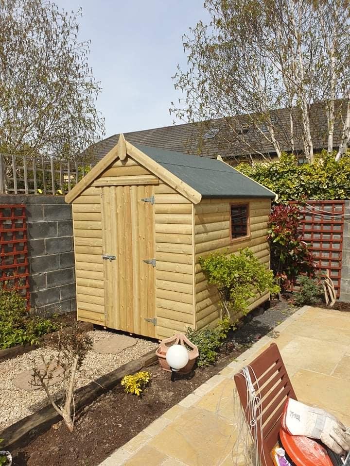 A small wooden shed is sitting in the middle of a garden.