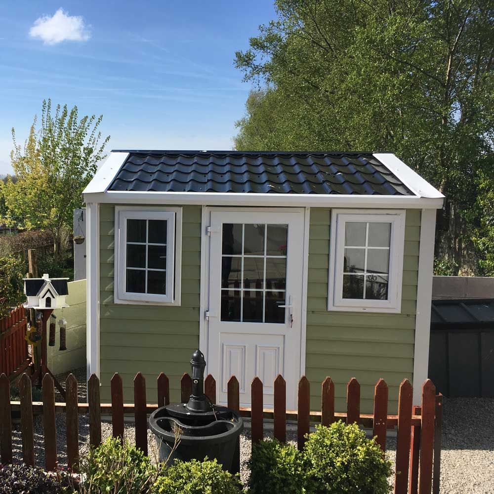 A green and white shed with a black roof