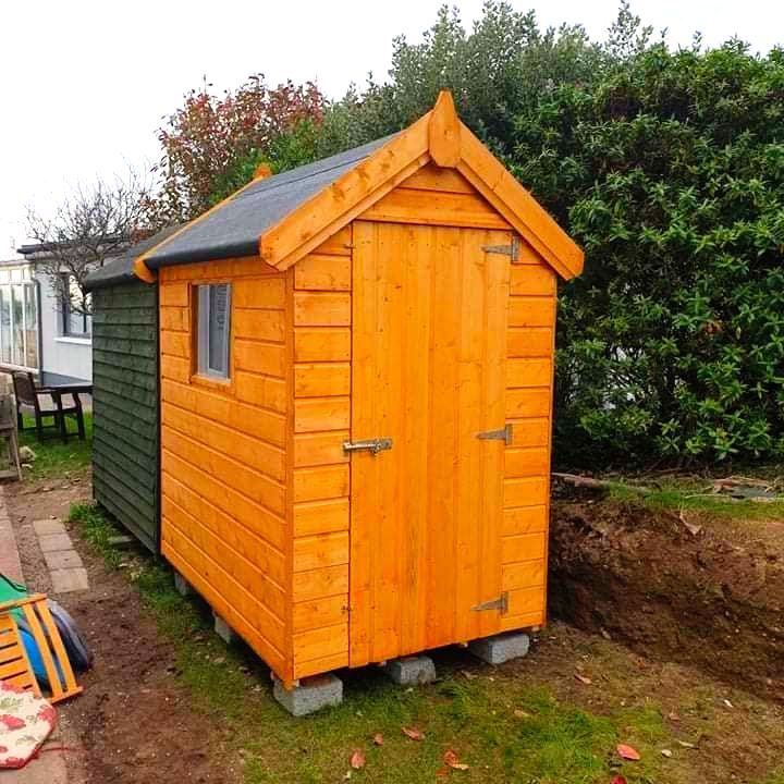 A small wooden shed with a window on the side of it