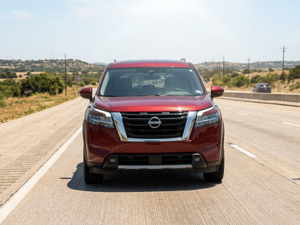 Front view of a red Nissan Pathfinder SUV driving on a sunny highway