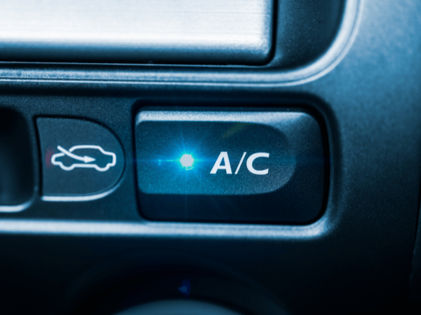 Close up of vehicle air conditioning button illuminated on car climate control panel