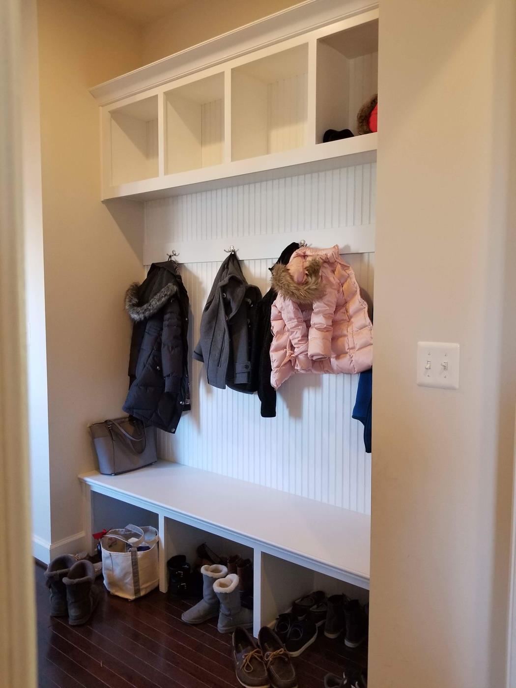 A hallway with a bench and jackets hanging on the wall