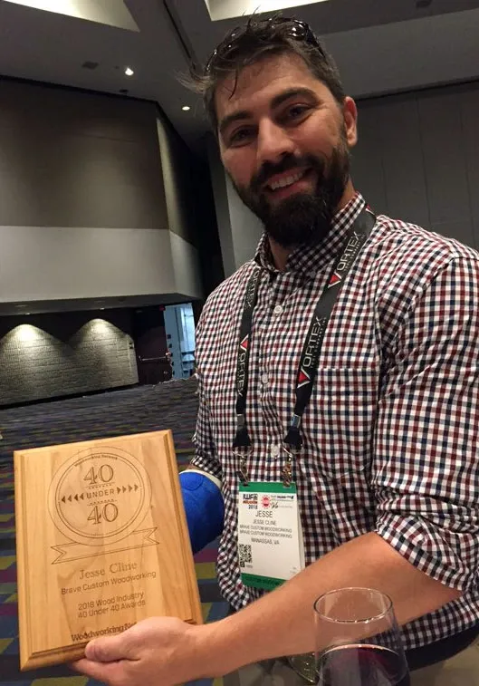 A man in a plaid shirt is holding a wooden plaque with the number 30 on it