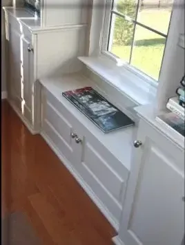 A book sits on a shelf next to a window