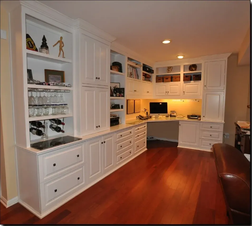 A corner of a room with white cabinets and drawers