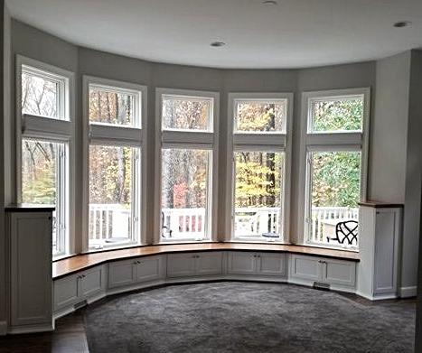 A room with a lot of windows and a curved window seat.