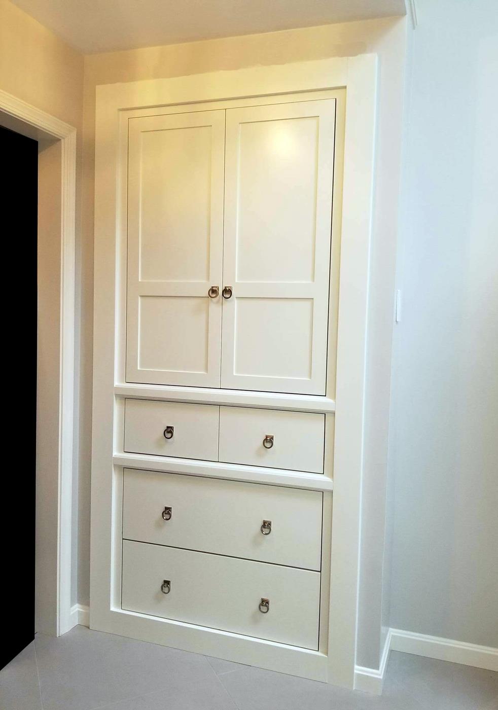 A white cabinet with drawers and doors in a room