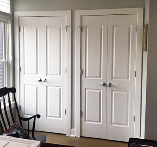 A room with two white doors and a black chair