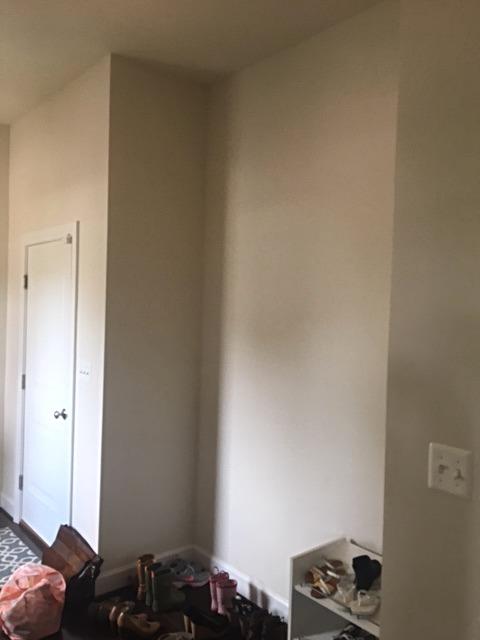A room with white walls , a shelf , and a door.
