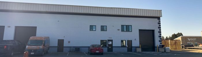 Three cars are parked in front of a large brick building.