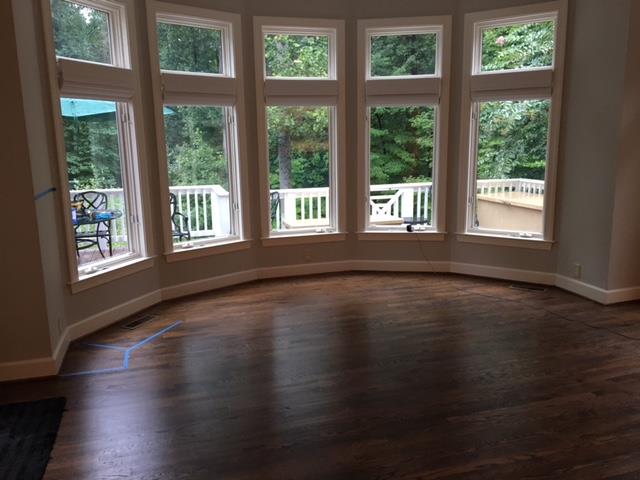 A living room with a lot of windows and a wooden floor.