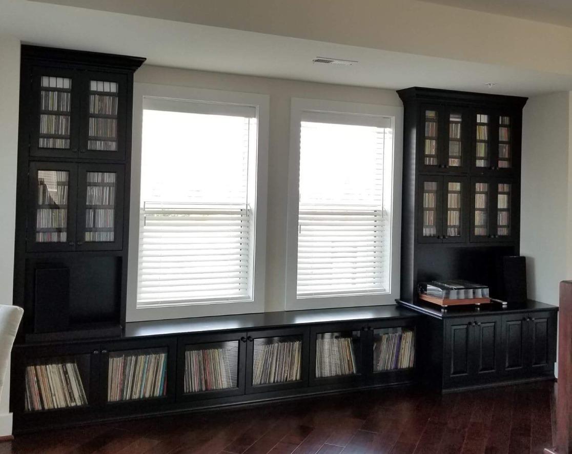 A living room with black cabinets and two windows